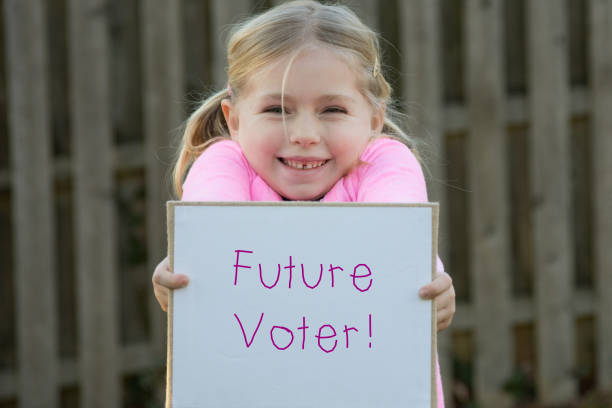 Blonde child holding up a sign that says Future Voter!